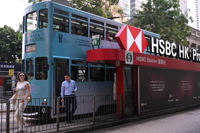 People alight from a tram outside the HSBC bank headquarters in Hong Kong on October 27, 2026, ahead of the bank's third quarter results announcement. (Photo by Peter PARKS / AFP)