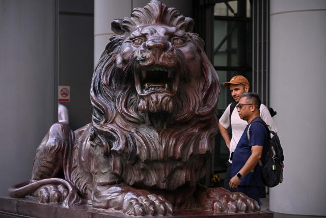 Visitors look at the bronze lion outside the HSBC bank headquarters in Hong Kong on October 27, 2026, ahead of the bank's third quarter results announcement. (Photo by Peter PARKS / AFP)