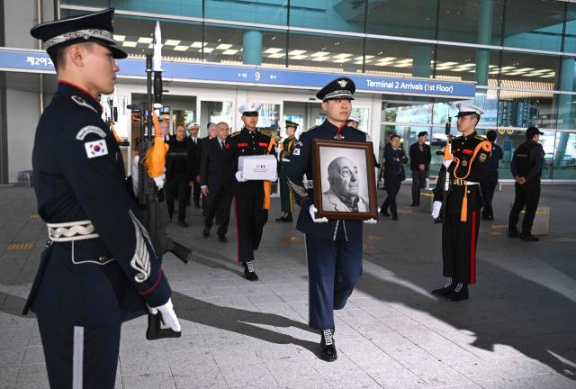 South Korean military honour guards carry the portrait and remains of French Korean War veteran Serge Gabriel Archambeau during a repatriation ceremony at Incheon International Airport in Incheon on October 27, 2026, before being interred at the UN Memorial Cemetery in Busan. (Photo by Jung Yeon-je / AFP)
