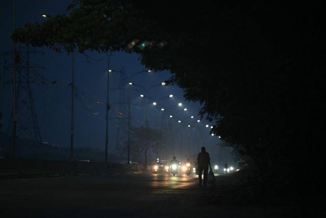 A pedestrian walks at roadside during the early morning, in Chennai on October 27, 2026. (Photo by R.Satish BABU / AFP)
