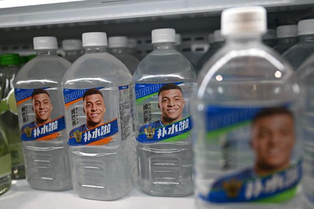 Bottles of Dongpeng Beverage Group's "Bushuila" electrolyte drink featuring French football star Kylian Mbappe on the packaging are displayed at a convenience store in Beijing on October 27, 2026. Kylian Mbappe was dropped October 27 by two major brands in China after a video circulated online in which the French football star apparently joked about former leader Mao Zedong. (Photo by Pedro PARDO / AFP)