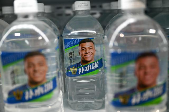 Bottles of Dongpeng Beverage Group's "Bushuila" electrolyte drink featuring French football star Kylian Mbappe on the packaging are displayed at a convenience store in Beijing on October 27, 2026. Kylian Mbappe was dropped October 27 by two major brands in China after a video circulated online in which the French football star apparently joked about former leader Mao Zedong. (Photo by Pedro PARDO / AFP)