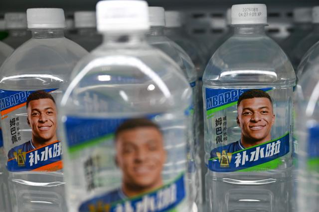 Bottles of Dongpeng Beverage Group's "Bushuila" electrolyte drink featuring French football star Kylian Mbappe on the packaging are displayed at a convenience store in Beijing on October 27, 2026. Kylian Mbappe was dropped October 27 by two major brands in China after a video circulated online in which the French football star apparently joked about former leader Mao Zedong. (Photo by Pedro PARDO / AFP)