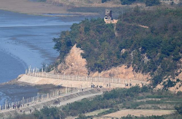 North Korean soldiers and workers along military fences on the North side of the Demilitarised Zone (DMZ) dividing the two Koreas, are seen from a South Korean observation deck at Aegibong Peace Ecopark in Gimpo on October 27, 2026. (Photo by Jung Yeon-je / AFP)
