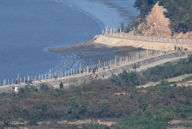 North Korean soldiers and workers along military fences on the North side of the Demilitarised Zone (DMZ) dividing the two Koreas, are seen from a South Korean observation deck at Aegibong Peace Ecopark in Gimpo on October 27, 2026. (Photo by Jung Yeon-je / AFP)