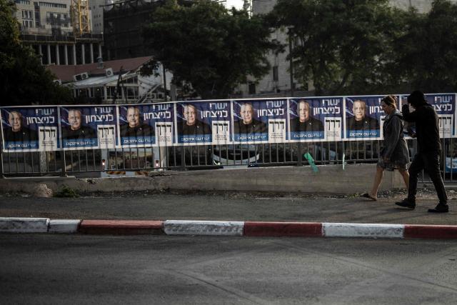 People walk past electoral banners of the Yashar party, led by Gadi Eisenkot, outside a polling station in Jerusalem on October 27, 2026, on the day of Israel's legislative election. A deeply divided Israel heads to the polls on October 27 for the first time since Hamas's October 7, 2023 attack, with voters delivering their verdict on veteran Prime Minister Benjamin Netanyahu and the country's rightward drift. (Photo by Jewel SAMAD / AFP)