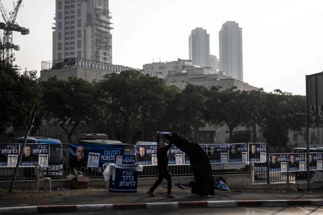 A supporter of the Yashar party, led by Gadi Eisenkot, arranges electoral banners outside a polling station in Jerusalem on October 27, 2026, on the day of Israel's legislative election. A deeply divided Israel heads to the polls on October 27 for the first time since Hamas's October 7, 2023 attack, with voters delivering their verdict on veteran Prime Minister Benjamin Netanyahu and the country's rightward drift. (Photo by Jewel SAMAD / AFP)