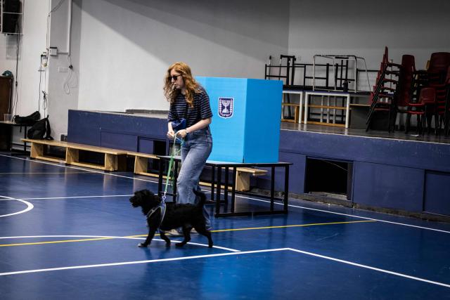 A woman and her dog leave the voting booth at a polling station in Jerusalem on October 27, 2026, on the day of Israel's legislative election. A deeply divided Israel heads to the polls on October 27 for the first time since Hamas's October 7, 2023 attack, with voters delivering their verdict on veteran Prime Minister Benjamin Netanyahu and the country's rightward drift. (Photo by John WESSELS / AFP)
