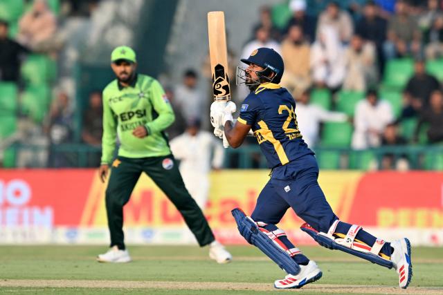Sri Lanka's Kamindu Mendis (R) watches the ball after playing a shot during the one-day international (ODI) tri-series cricket match between Pakistan and Sri Lanka at the Gaddafi Stadium in Lahore on October 27, 2026. (Photo by ARIF ALI / AFP)