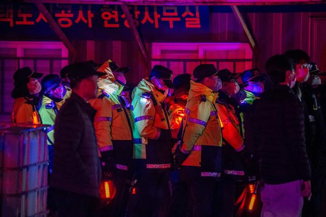 Firefighters and police officers work at the scene of a fire in the shanty village of Guryong on the outskirts of Gangnam district in Seoul on October 27, 2026. (Photo by Philip FONG / AFP)