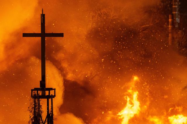 A church's cross tower is seen at the scene of a fire in the shanty village of Guryong on the outskirts of Gangnam district in Seoul on October 27, 2026 (Photo by Philip FONG / AFP)