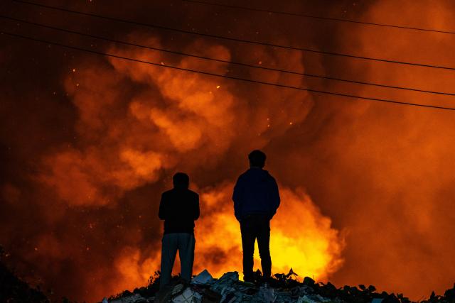 Bystanders look at the scene of a fire in the shanty village of Guryong on the outskirts of Gangnam district in Seoul on October 27, 2026. (Photo by Philip FONG / AFP)