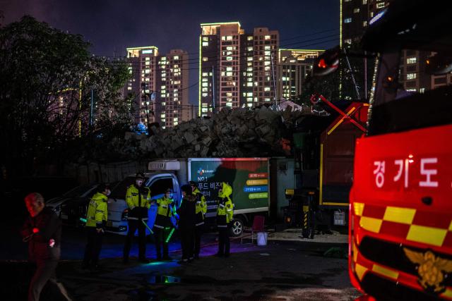 Police officers stand guard at the scene of a fire in the shanty village of Guryong on the outskirts of Gangnam district in Seoul on October 27, 2026. (Photo by Philip FONG / AFP)
