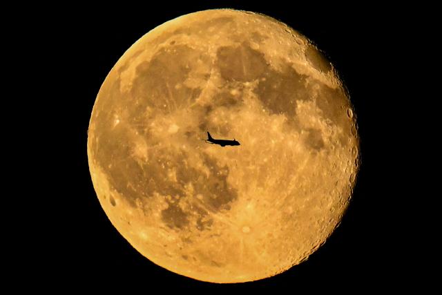 An Embraer E190LR aircraft of Swiss airline Helvetic airways flies past the Waning gibbous moon over Frankfurt am Main, western Germany on October 27, 2026, one day after full moon, also known as Hunter's moon. (Photo by Kirill KUDRYAVTSEV / AFP)