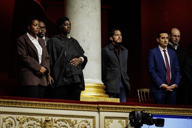 Mayor of Trappes Ali Rabeh (C) obersves a minute of silence to pay tribute to Pengo Bossio Wangi, the man killed in the racist shooting that took place on October 23 in Trappes in which five other people were also wounded, ahead of a session of questions to the government at The National Assembly, France's lower house of parliament in Paris on October 27, 2026. (Photo by Simon WOHLFAHRT / AFP)