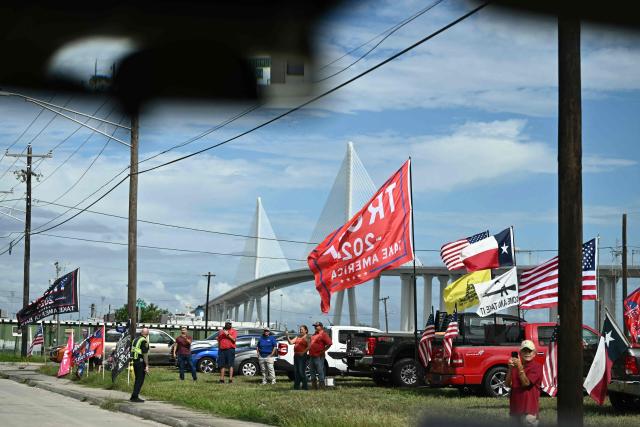 Supporters of US President Donald Trump hold flags as he arrives in Corpus Christi, Texas on October 27, 2026. President Trump is travelling to Texas to attend midterm campaign rallies. (Photo by Kent NISHIMURA / AFP)
