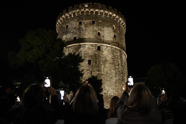 People photograph the White Tower illuminated by a new lighting system in Thessaloniki on October 27, 2026. (Photo by Sakis Mitrolidis / AFP)