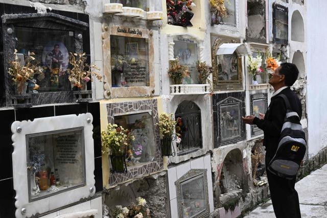 A man prays in front of a relative's cemetery niche at the General Cemetery in La Paz on October 27, 2026, ahead of All Saints' Day celebrations. (Photo by Aizar RALDES / AFP)