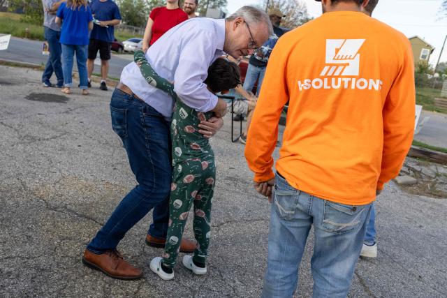 Democrat senatorial candidate from Kansas Adam Hamilton hugs a young supporter outside of Wilson’s Pizza in Kansas City, Kansas on October 27, 2026. Democratic pastor Adam Hamilton is challenging Republican Roger Marshall in a state that has not elected a Democratic senator since 1932. Tight polling has prompted Trump to campaign for Marshall. (Photo by Austin Johnson / AFP)