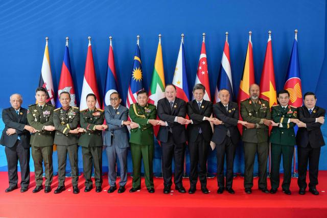 (L-R) Brunei's Defence Minister Halbi Mohammad Yussof, Cambodia’s Defence State Secretary Rath Dararoth, Indonesia’s Defence Vice Minister Richard Tampubolon, Laos' Defence Minister Khamlieng Outhakaisone, Malaysia's Defence Minister Mohamed Khaled Nordin, Myanmar’s Defence Attache to the Philippine Tun Tun San, Philippines' Defence Secretary Gilberto Teodoro, Singapore's Defence Minister Chan Chun Sing, Thailand’s Deputy Permanent Secretary for Defence Amarit Boonsuya, East Timor’s Chief of Defence Force Falur Rate Laek, Vietnam's Defence Minister Phan Van Giang and ASEAN Secretary-General Dr. Kao Kim Hourn link arms as they pose for a family photo at the opening ceremony of the 20th Association of Southeast Asian Nations (ASEAN) Defence Ministers' Meeting in Cebu, central Philippines on October 28, 2026. (Photo by Aaron Favila / POOL / AFP)