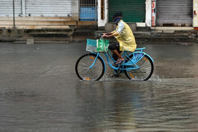 A man cycles through a water-logged street in Andhra Pradesh's Kakinada on October 28, 2026, ahead of cyclone Arnab's expected landfall. (Photo by Noah SEELAM / AFP)