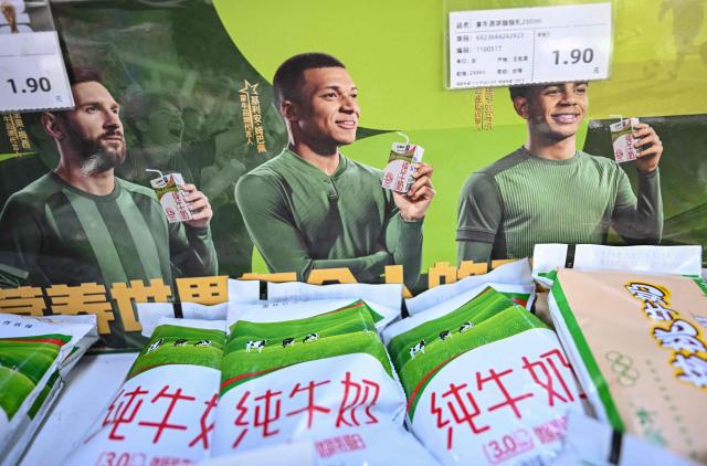 This photo shows an advertising campaign for Chinese dairy brand 'Mengniu' featuring football stars France's Kylian Mbappe (C), Argentina's Lionel Messi (L) and Spain's Lamine Yamal at a supermarket in Beijing on October 28, 2026. Kylian Mbappe apologised on October 27, after the Real Madrid star was dropped by major Chinese brands for apparently joking about Mao Zedong in a video that has gone viral. (Photo by Pedro PARDO / AFP)