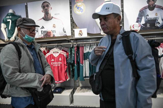 Customers stand in the Real Madrid football jerseys section at an Adidas store in Beijing on October 28, 2026. Kylian Mbappe apologised on October 27, after the Real Madrid star was dropped by major Chinese brands for apparently joking about Mao Zedong in a video that has gone viral. (Photo by Pedro PARDO / AFP)