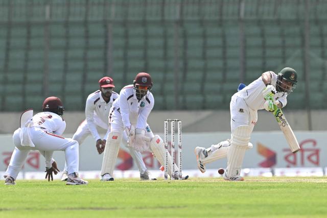 Bangladesh's captain Najmul Hossain Shanto (R) plays a shot as West Indies' wicketkeeper Amir Jangoo (2R) watches during the first day of the first test cricket match between Bangladesh and West Indies at the Sher-e-Bangla National Stadium in Mirpur on October 28, 2026. (Photo by Salahuddin Ahmed / AFP)