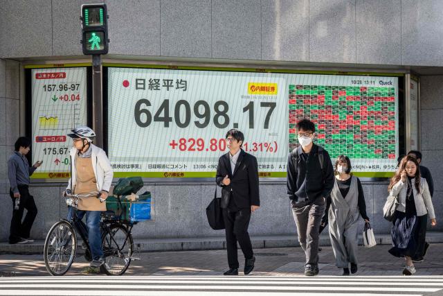 People walk past an electronic quotation board displaying the Nikkei Stock Average on the Tokyo Stock Exchange in Tokyo on October 28, 2026. (Photo by Yuichi YAMAZAKI / AFP)