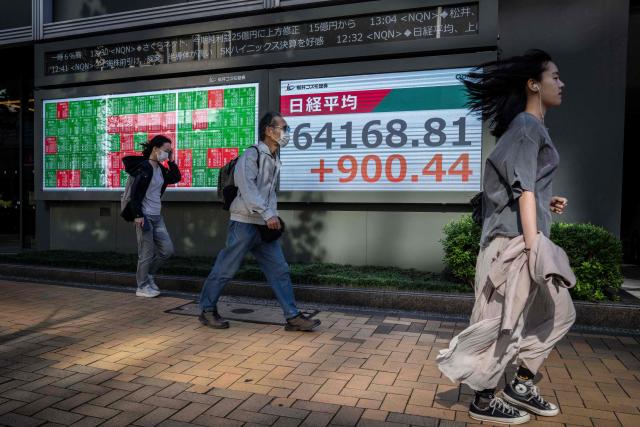 People walk past an electronic quotation board displaying the Nikkei Stock Average on the Tokyo Stock Exchange in Tokyo on October 28, 2026. (Photo by Yuichi YAMAZAKI / AFP)