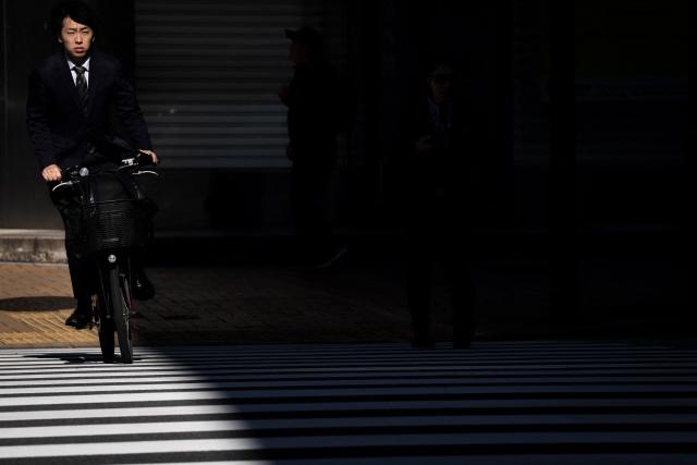 TOPSHOT - A man riding a bicycle crosses a street in Tokyo on October 28, 2026. (Photo by Yuichi YAMAZAKI / AFP)