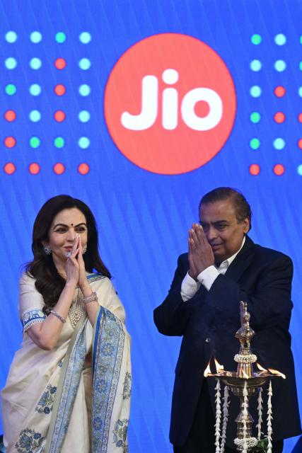 Indian billionaire and Reliance Industries chairman Mukesh Ambani (R) with his wife Nita Ambani greets the audience during the initial public offering (IPO) listing ceremony of Reliance Industries' Jio Platforms at the National Stock Exchange (NSE) in Mumbai on October 28, 2026. Shares in India's Jio Platforms surged more than 21 percent on its market debut on October 28, after raising more than $3 billion in the country's biggest initial public offering. (Photo by Indranil MUKHERJEE / AFP)