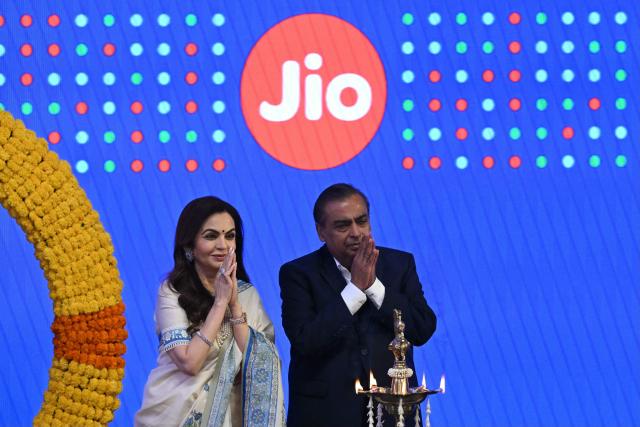 Indian billionaire and Reliance Industries chairman Mukesh Ambani (R) with his wife Nita Ambani greets the audience during the initial public offering (IPO) listing ceremony of Reliance Industries' Jio Platforms at the National Stock Exchange (NSE) in Mumbai on October 28, 2026. Shares in India's Jio Platforms surged more than 21 percent on its market debut on October 28, after raising more than $3 billion in the country's biggest initial public offering. (Photo by Indranil MUKHERJEE / AFP)