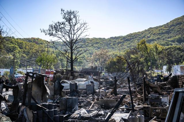 A photojournalist take pictures next to burnt-out buildings a day after a fire in the shanty village of Guryong on the outskirts of Gangnam district in Seoul on October 28, 2026.  (Photo by Philip FONG / AFP)