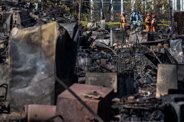 Firefighters work next to burnt-out buildings a day after a fire in the shanty village of Guryong on the outskirts of Gangnam district in Seoul on October 28, 2026.  (Photo by Philip FONG / AFP)