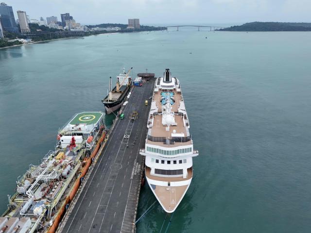 An aerial view shows the Villa Vie Residences' cruise ship Odyssey docked at Sihanoukville port in Preah Sihanouk province on October 28, 2026. Around 200 passengers who paid to live on a cruise ship while travelling the world were abruptly left in a Cambodian port after the company ran out of money, an official said on October 28. (Photo by Suy Se / AFP)