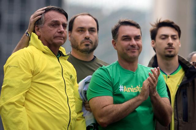 (FILES) (FILES) Michelle Bolsonaro (R) speaks as her husband Brazil's former President Jair Bolsonaro (L) and his sons Carlos (2-L), Flavio (C) and Renan listen during a rally at Paulista Avenue in Sao Paulo, Brazil, on April 6, 2025. Defeated right-wing presidential candidate Flavio Bolsonaro was on his way to Ecuador after fleeing Brazil, Argentina's government said on October 28, 2026. Bolsonaro entered Argentina the night before before boarding a flight to Ecuador, the country's National Directorate of Migration said on X. (Photo by Miguel SCHINCARIOL / AFP)