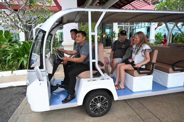 Villa Vie Residences’ Odyssey cruise ship passengers sit on an EV vehicle at a hotel in Sihanoukville, Preah Sihanouk province, on October 28, 2026. Around 200 passengers who paid to live on a cruise ship while travelling the world were abruptly left in a Cambodian port after the company ran out of money, an official said on October 28. (Photo by TANG CHHIN Sothy / AFP)