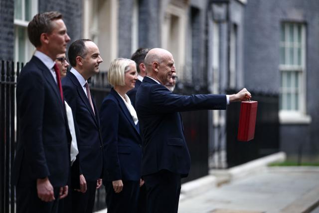 Britain's Chancellor of the Exchequer John Healey holds aloft the red Budget Box as he poses with members of his treasury team, Britain's Chief Secretary to the Treasury Emma Reynolds, Britain's Financial Secretary to the Treasury James Murray, Britain's Economic Secretary to the Treasury Lucy Rigby, Britain's Exchequer Secretary to the Treasury Dan Tomlinson, Britain's Minister for Pensions Torsten Bell and Britain's Parliamentary Secretary at the Treasury David Pitt-Watson, as he leaves 11 Downing Street in central London on October 28, 2026, before presenting the government's annual budget to Parliament. On Wednesday, John Healey will present his first budget, which will test its ability to support purchasing power and increase defence spending, all while working with limited financial leeway. (Photo by Henry NICHOLLS / AFP)