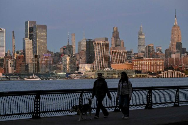 People walk during sunset on October 27, 2026 in New York City. (Photo by ANGELA WEISS / AFP)