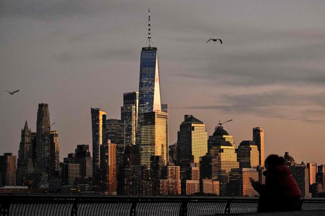 A person watches the sunset of the lower Manhattan skyline and One World Trade Center in New York on October 27, 2026. (Photo by ANGELA WEISS / AFP)