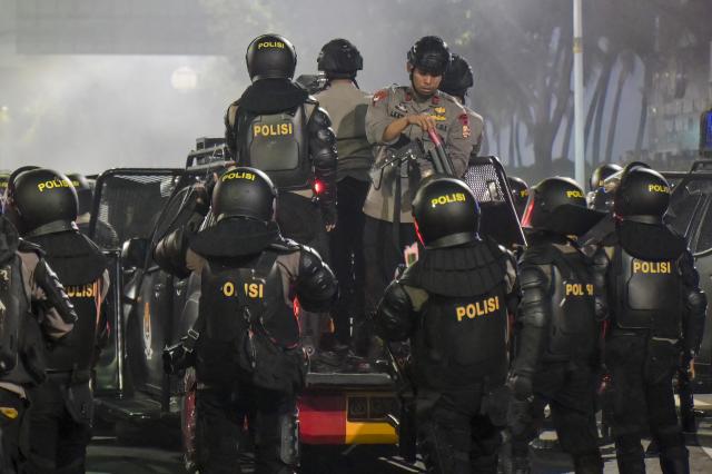 Riot police officers load tear gas launchers atop a tactical vehicle during clashes with demonstrators protesting against economic hardship, alleged government corruption, and toxic haze from wildfires, in Jakarta on October 28, 2026. (Photo by BAY ISMOYO / AFP)