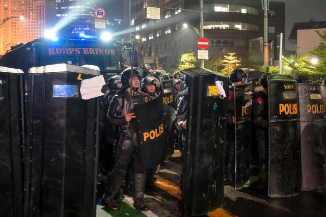 Indonesian riot police form a barricade with shields backed by a water cannon vehicle during a demonstration against economic hardship, alleged government corruption, and toxic haze from wildfires, in Jakarta on October 28, 2026. (Photo by BAY ISMOYO / AFP)