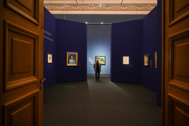 A visitor walks between Gauguin's works during the press preview of an exhibition titled "Bonjour Monsieur Gauguin – The Circles of Post-Impressionists and Symbolists" at the Museum of Fine Arts in Budapest on October 28, 2026. The first major Hungarian exhibition dedicated to French painter Paul Gauguin features 80 of his works, alongside masterpieces by artists such as Gustave Courbet, Camille Pissarro, Claude Monet, Paul Cezanne, Vincent van Gogh, Emile Bernard, and Paul Serusier. The exhibition was realized through the collaboration of Budapest's museum and over 40 lending institutions, including the Musйe d’Orsay in Paris, the Metropolitan Museum of Art and the Museum of Modern Art (MoMA) in New York, the National Gallery of Art in Washington, the Van Gogh Museum in Amsterdam, the Tate in London, and the Museo Nacional Thyssen-Bornemisza in Madrid. The exhibition officially opens on October 30 and will be running until February 28, 2027. (Photo by Attila KISBENEDEK / AFP)