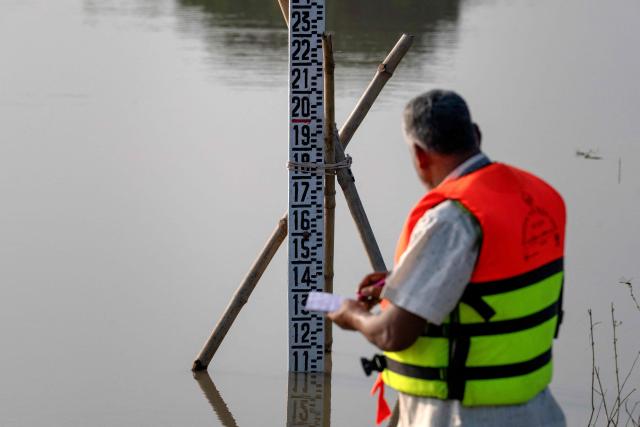 This photograph taken on October 13, 2026 shows Bangladesh Water Development Board's gauge reader Nazir Uddin recording Padma river's water-level in Ujirpur, near the Bangladesh-India frontier in Bangladesh's Rajshahi division. Bangladesh is blighted by persistent water shortages -- and the expiration of a 1996 water-sharing treaty with neighbouring India in just a few weeks' time threatens tens of millions of livelihoods. The deal governing the cross-border river Ganges, known in Bangladesh as the Padma, is set to expire on December 12. (Photo by Salahuddin Ahmed / AFP)