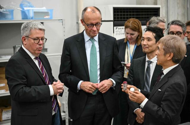 Germany's Chancellor Friedrich Merz (C) stands next to Kyoto Fusioneering CEO Satoshi Konishi (R) and head of Kyoto Fusioneering Europe Christian Day (L) during a visit of Kyoto Fusioneering company in Tokyo on October 29, 2026. (Photo by Yuichi YAMAZAKI / AFP)