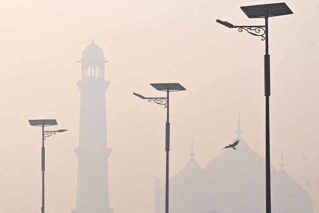 A bird flies past in the backdrop of a monument amid smog in Lahore on October 29, 2026. (Photo by Arif ALI / AFP)