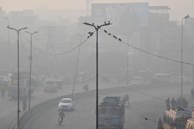 Commuters ride along a street amid smog in Lahore on October 29, 2026. (Photo by Arif ALI / AFP)