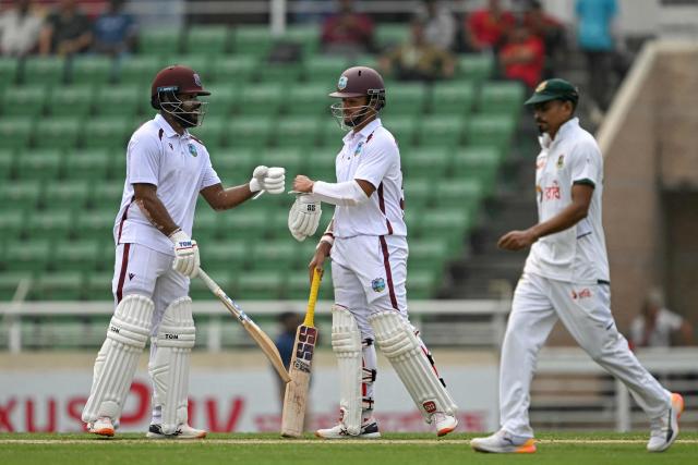 West Indies' John Campbell (L) and Tagenarine Chanderpaul (C) bump their fists during the second day of the first test cricket match between Bangladesh and West Indies at the Sher-e-Bangla National Stadium in Mirpur on October 29, 2026. (Photo by Salahuddin Ahmed / AFP)