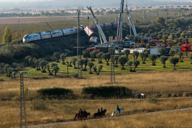 Spanish mounted police survey the perimiter around the damaged carriages of a train crash between two high-speed units, a Renfe AVE train and an Iryo train around 150 km south of Madrid between Urda and Los Yebenes in the province of Toledo, a day after the accident on October 29, 2026. A high-speed train collision south of Madrid killed 68 people and injured scores more, authorities said, in one of Europe's deadliest such disasters this century. The second such accident to strike Spain this year will raise fresh questions about the country's rail safety, with the transport minister speaking of an "error" and "inexplicable circumstances" that led to the crash. (Photo by Oscar DEL POZO / AFP)